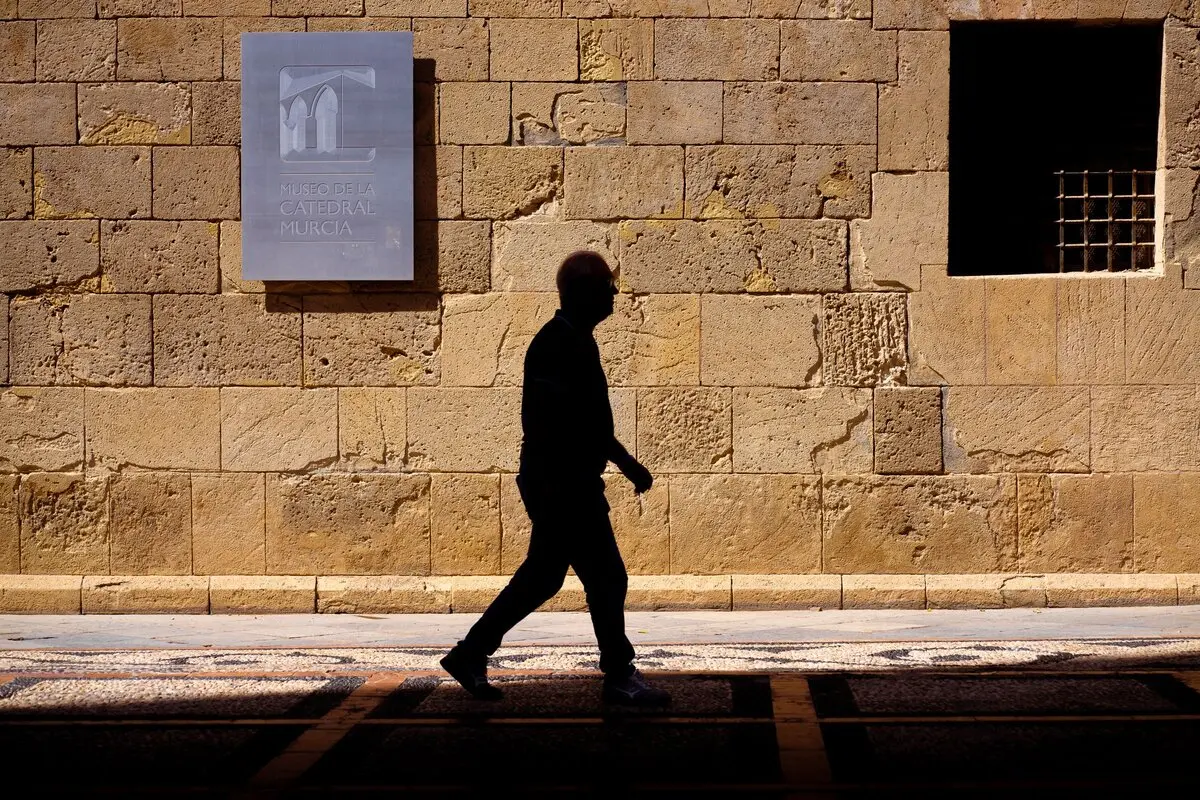 Un hombre pasea junto al muro del Museo de la Catedral de Murcia